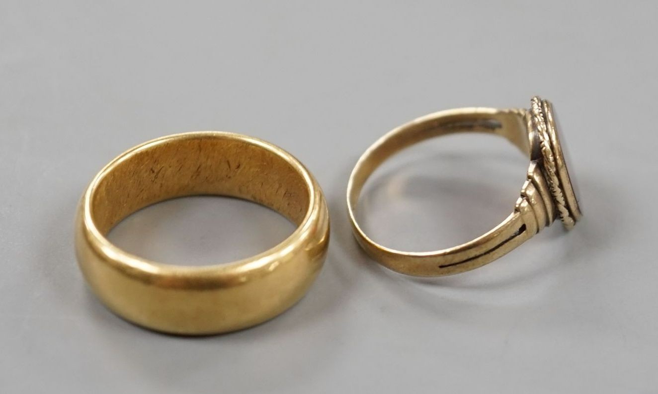 A George V 18ct gold wedding band, size Q, 14 grams and a 333 standard yellow metal and carnelian set signet ring, size R, gross weight 2.8 grams.